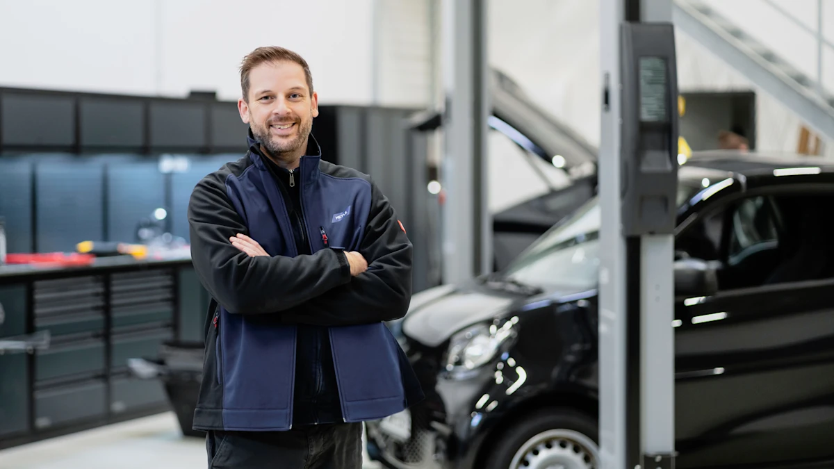 Christopher Timm steht lächelnd mit verschränkten Armen in der EV Experience Werkstatt.