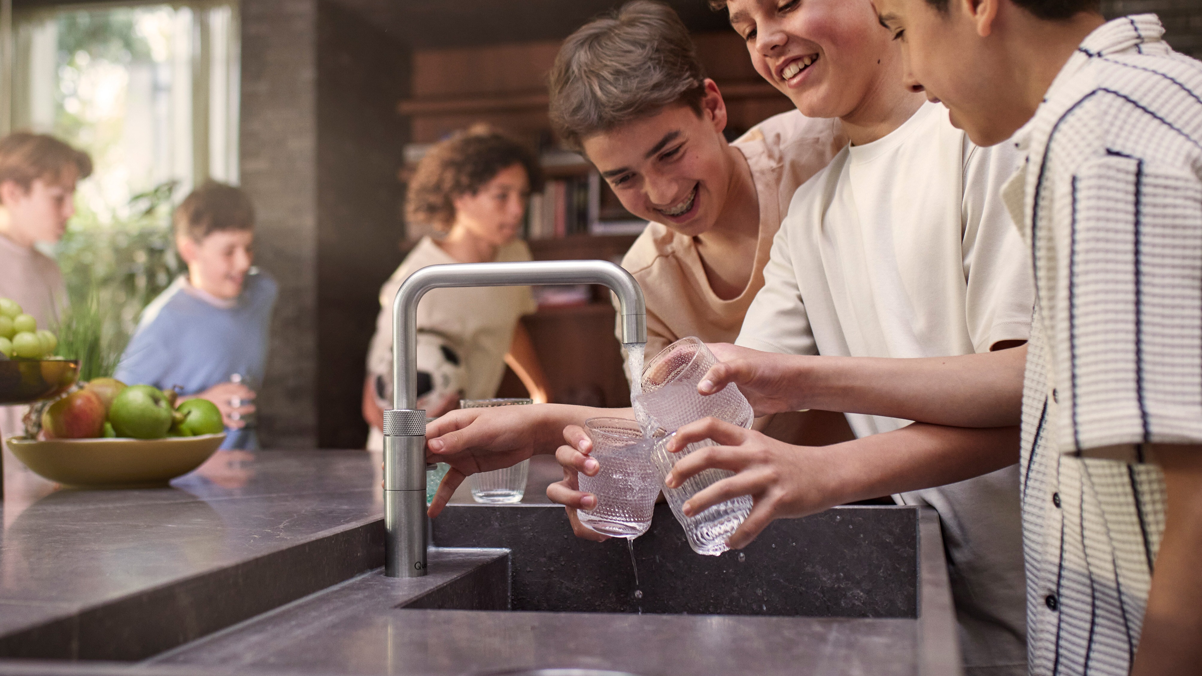 Kinder zapfen Sprudelwasser am Quooker