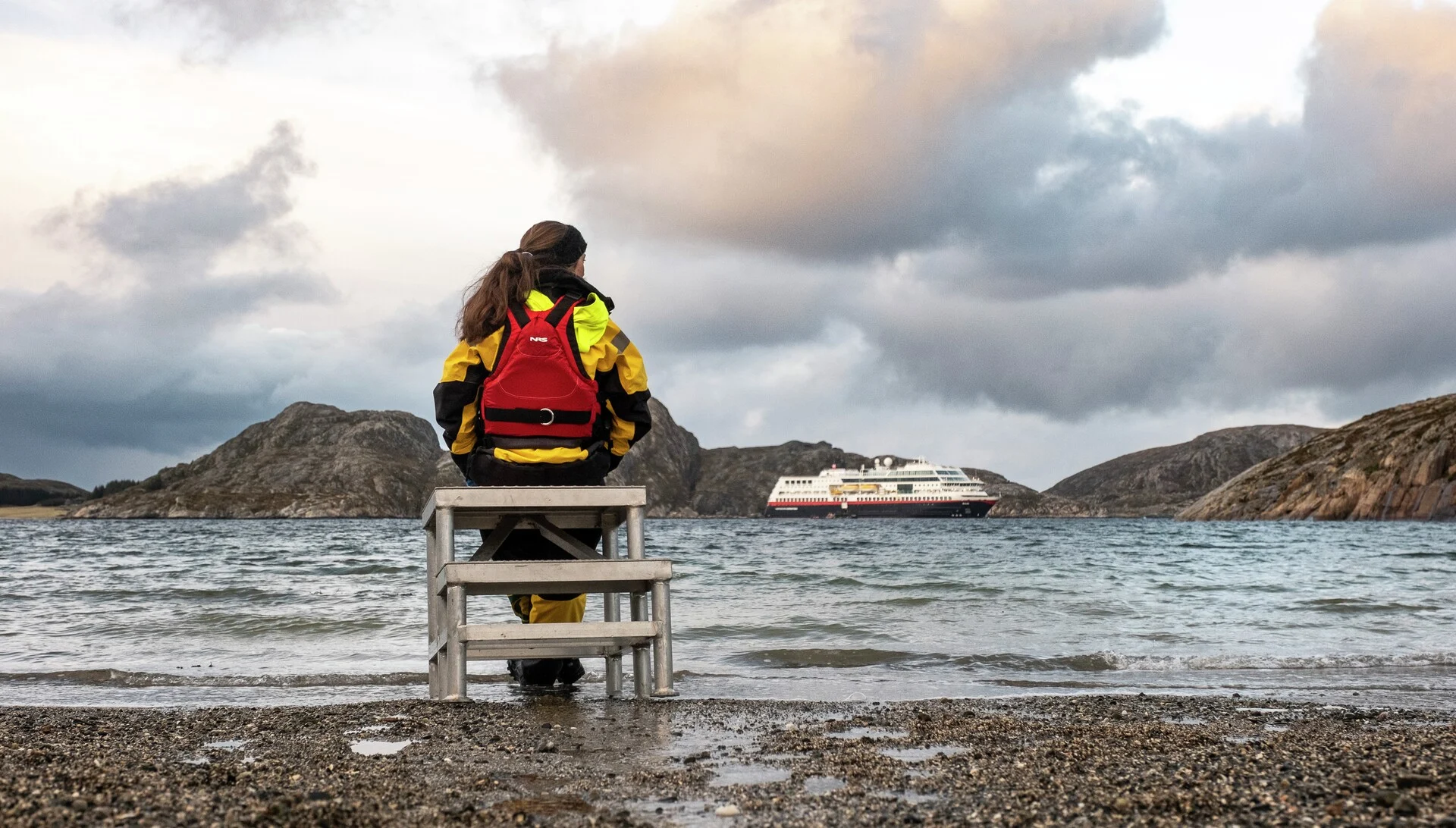 Expedition team member sitting in front of MS Fram anchored off Børøya, Norway with HX Hurtigruten Expeditions. Photo: Tommy Simonsen.