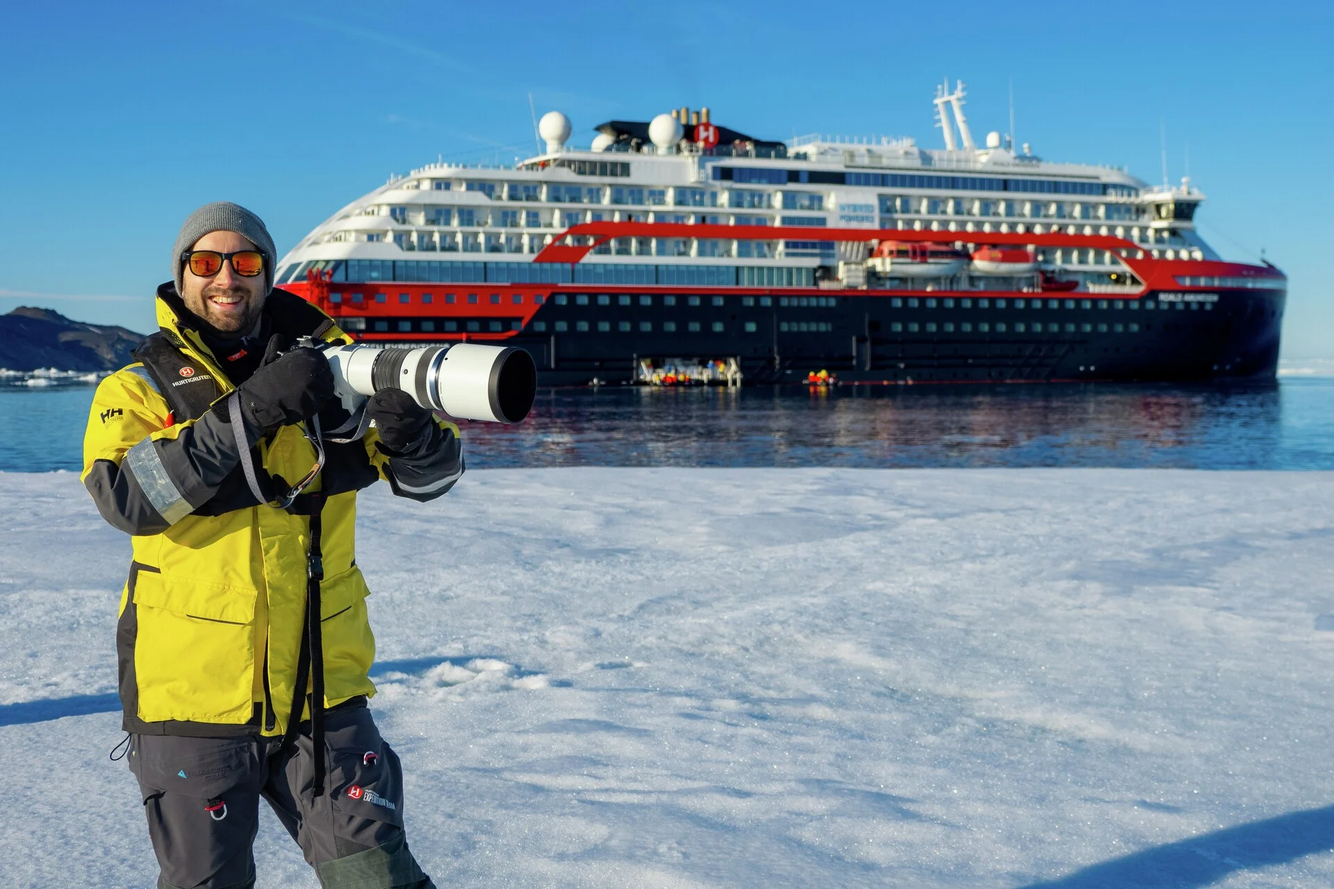 An Expedition team member on the ice in front of MS Roald Amundsen on the coast of Snowhill Island, Antarctica. Credit: Espen Mills.