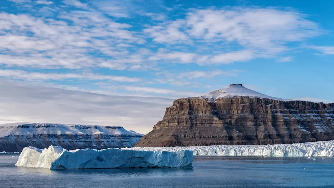 An iceberg in front of the large glacier of Devon Island in Crocker Bay, Canada. Credit:  John Chardine / Hurtigruten Expeditions