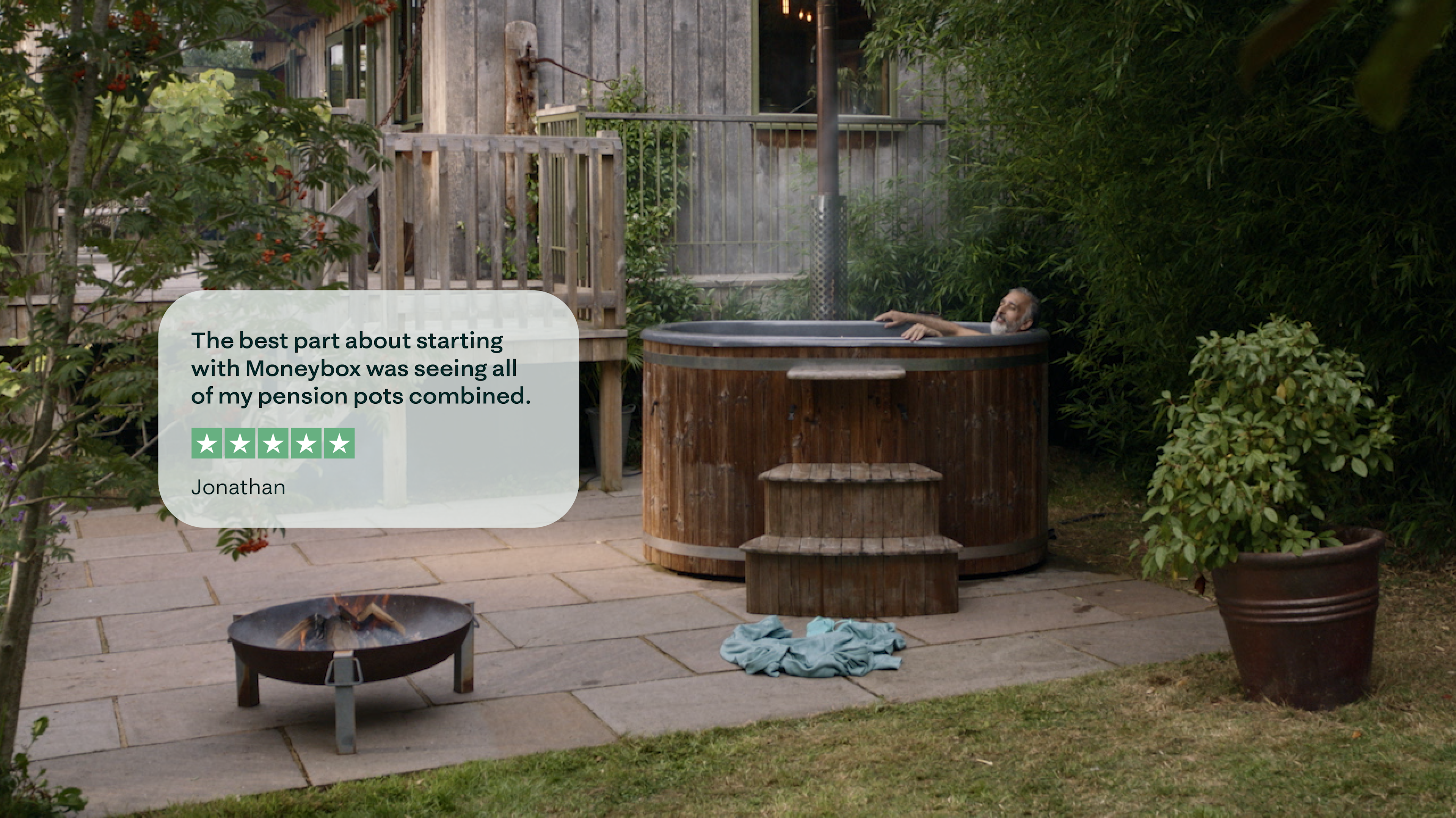 A zoomed out photograph of a man relaxing in a hot tub, with a trustpilot review overlayed