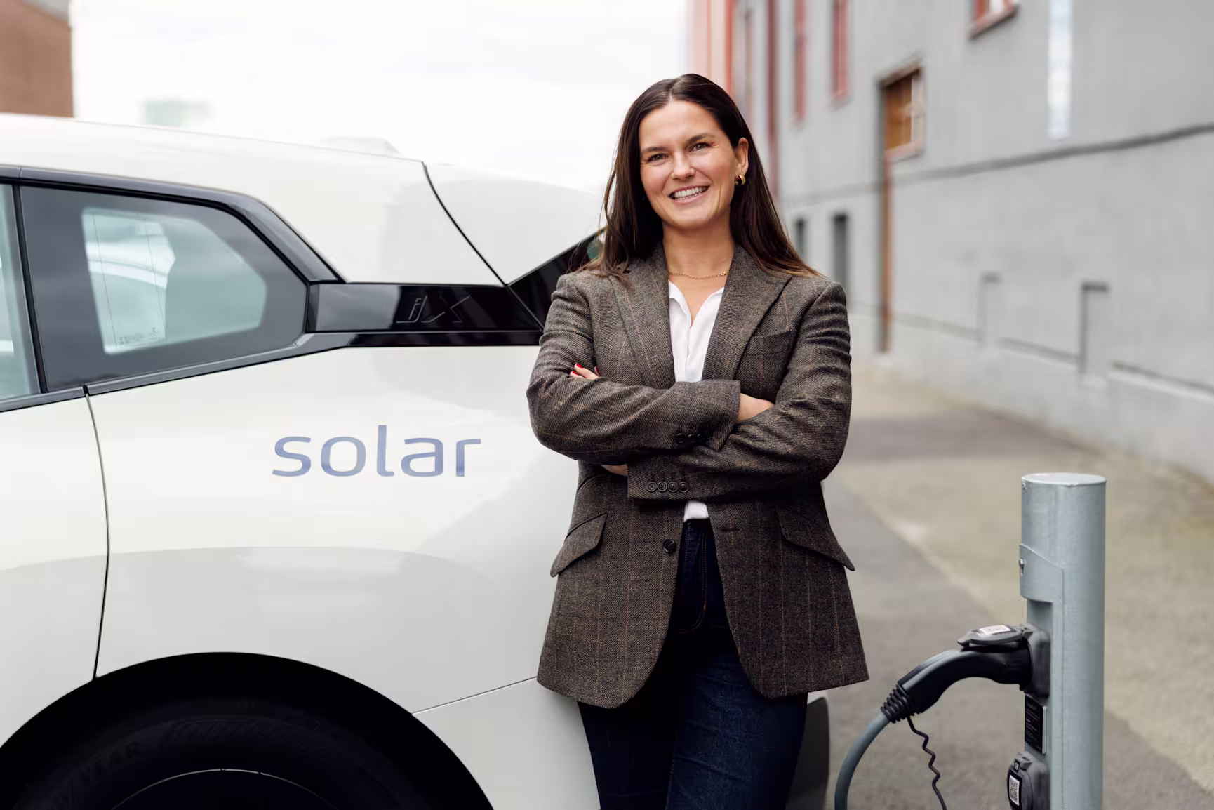 Woman in front of electrical car and EV charger
