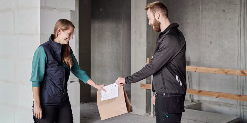 Man delivering Fastbox to woman at construction site