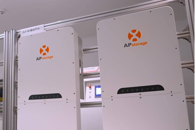 Twee witte APstorage-units die op een metalen frame zijn gemonteerd in een lichte ruimte. Zichtbare kabels zijn onderaan aangesloten, wat wijst op een schone en hightech energieopstelling.