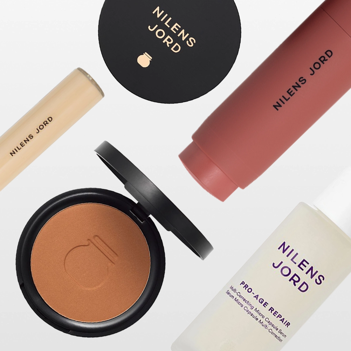 En samling av Nilens Jord skönhetsprodukter, inklusive en concealer, ett kompaktpuder, en ansiktskräm och en ansiktsserum. Produkterna är stilfullt arrangerade mot en vit bakgrund.