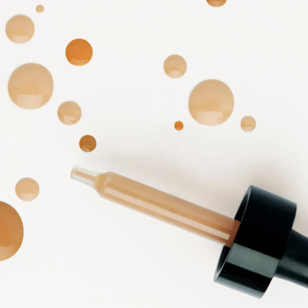 En pipett med bb cream och flera droppar av produkten på en vit bakgrund.
