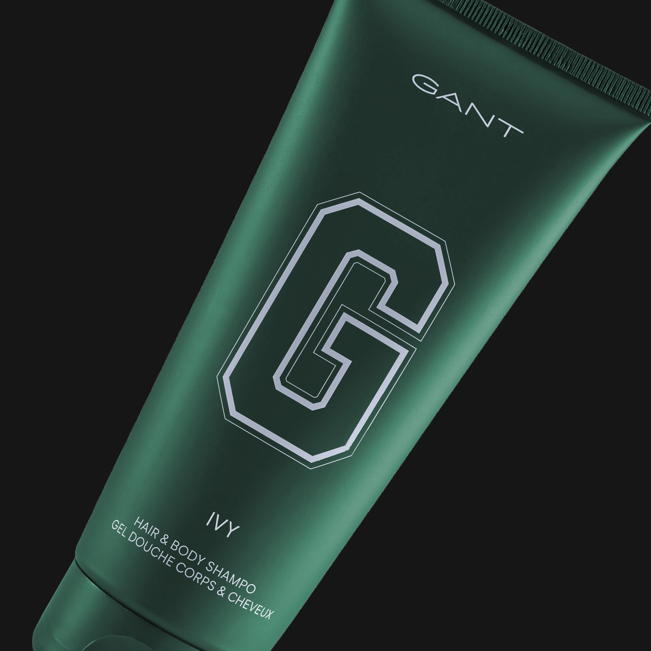 GANT Ivy Hair & Body Shampoo tummanvihreässä tuubissa mustaa taustaa vasten. Näkyvä teksti sisältää “GANT”, “G”, “IVY” ja “HAIR & BODY SHAMPOO”.