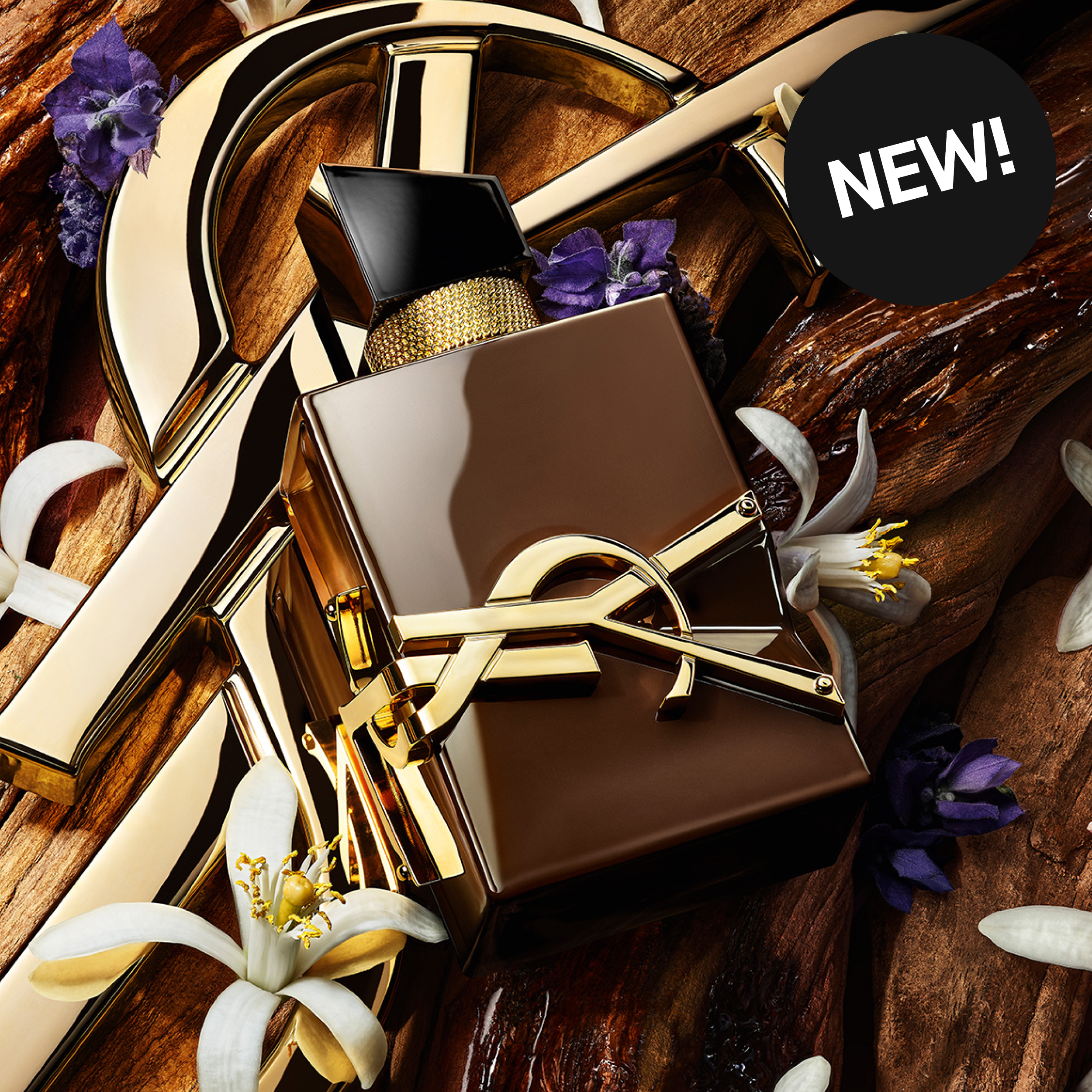 YSL-parfymeflaske omgitt av treverk og blomster. Tekst: «NEW!»