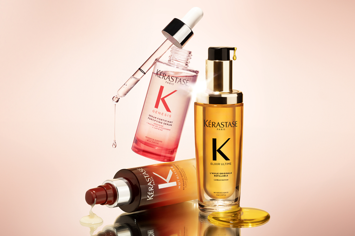 Tre bestselgende produkter fra Kerastase står lent mot hverandre mot en lys rosa bakgrunn