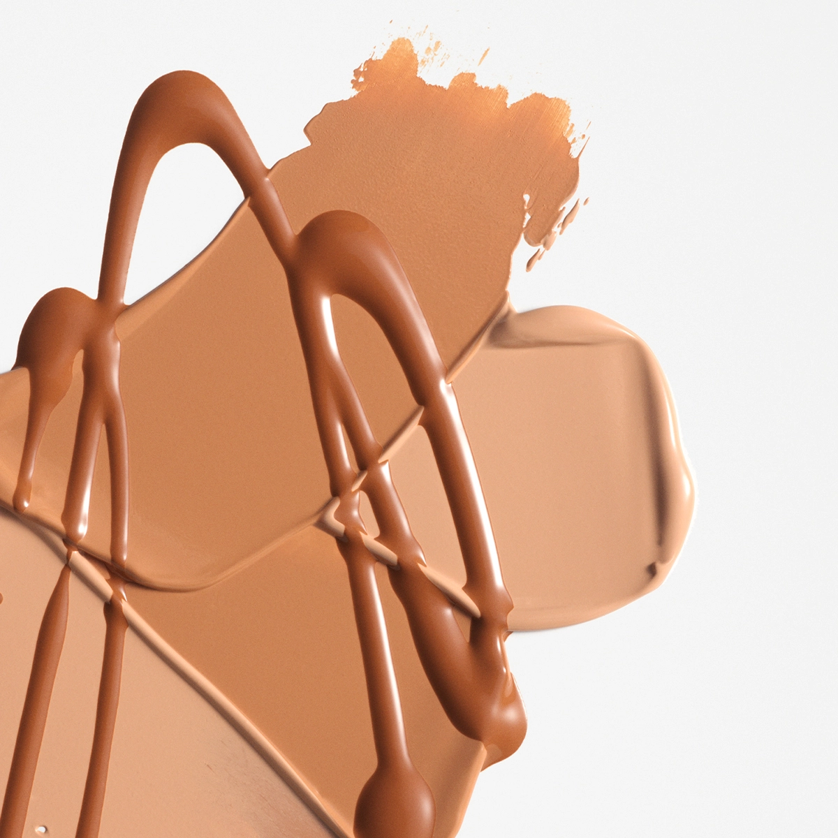 Nærbilde av kremet foundation eller concealer i beige nyanse smurt ut i brede strøk med blanke dråper oppå mot lys bakgrunn. Flytende makeup i nøytral tone med synlig tekstur og dekkende finish.