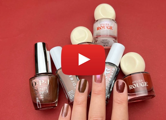 Hand med naglar målade i olika bruna nyanser som Chocolate glazed donut nails, Hailey Biebers senaste trendmanikyr. Nagellacksflaskor ligger bredvid.