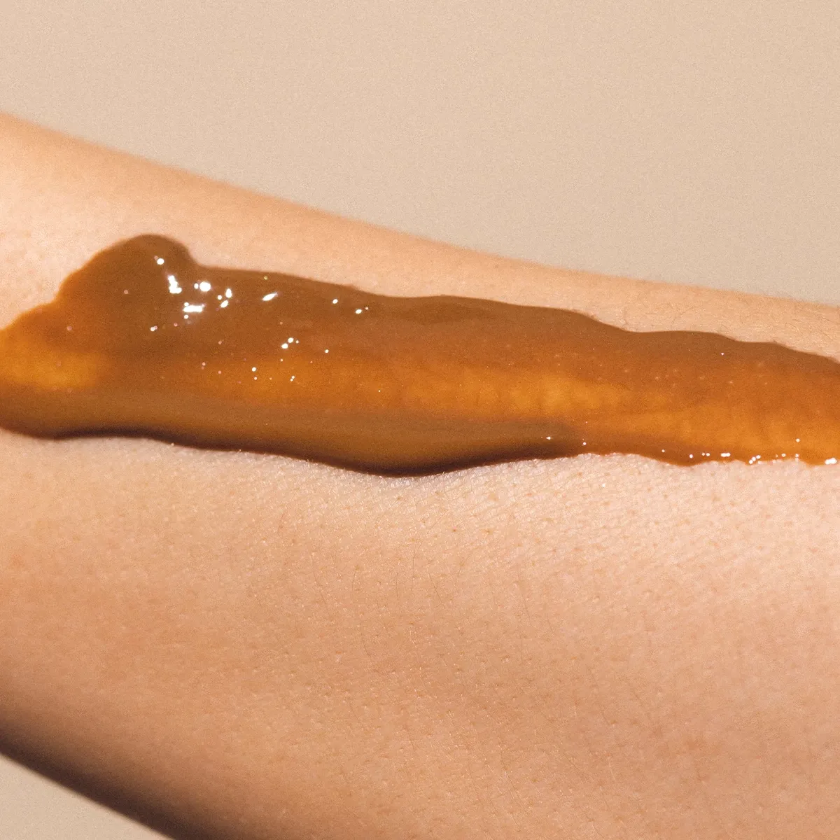 En närbild av en arm med en brun creme applicerad på huden.