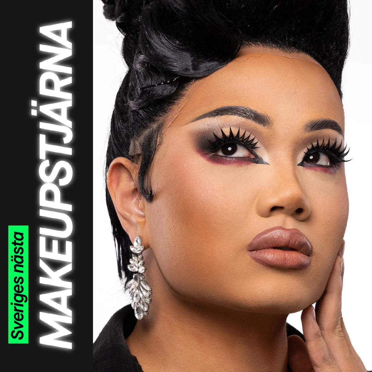 En person med en elegant makeuplook som kombinerar markerad ögonmakeup i guld, svart och vinrött med långa fransar, skulpterad bas och neutrala läppar, kompletterat med stora glittrande örhängen och en uppsatt frisyr.