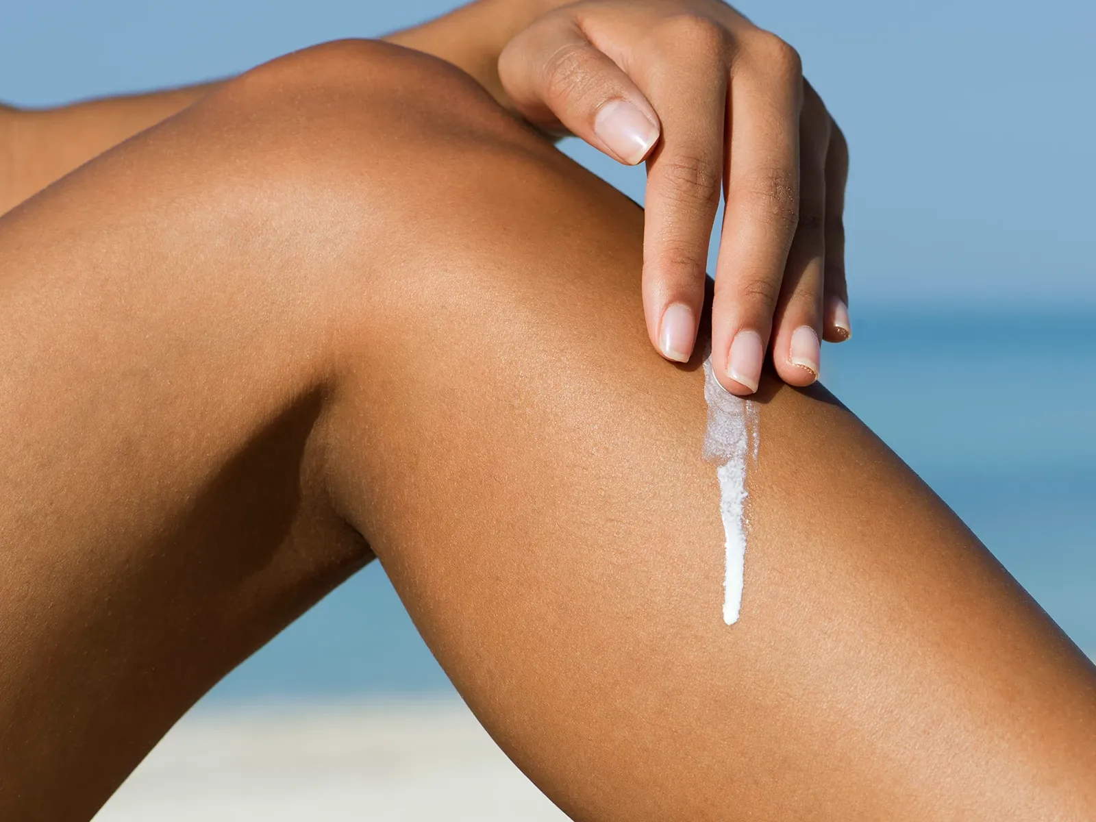 Person som smörjer in solkräm på sitt smalben
