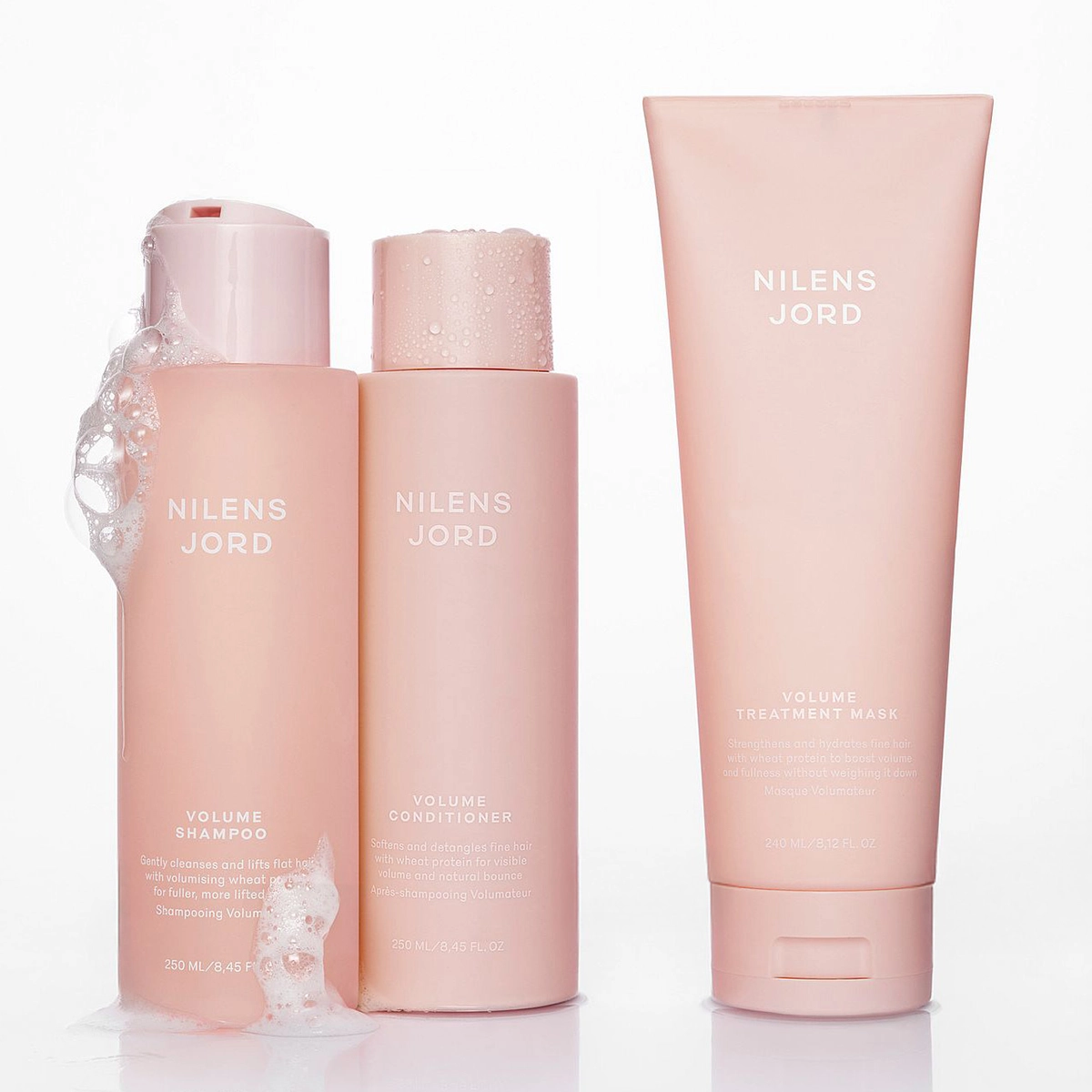 Kolme vaaleanpunaista Nilens Jord hiustuotetta: Volume Shampoo vaahdolla, Volume Hoitoaine ja Volume Hoitonaamio.