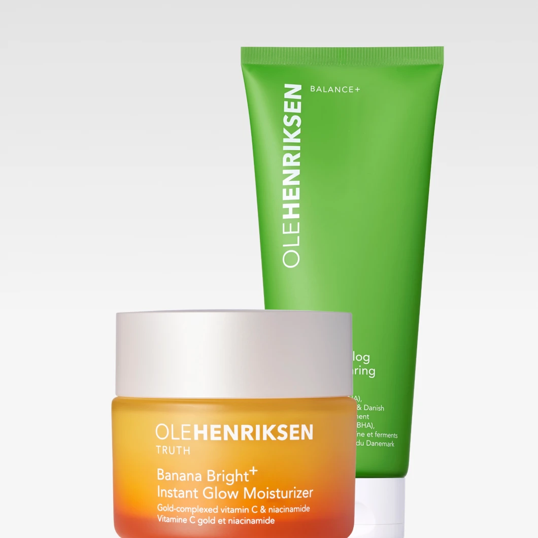 "To hudpleieprodukter fra Ole Henriksen plassert mot en lys bakgrunn: en oransje kremkrukke i glass og en grønn tube bak den. Krukken har et frostet utseende med hvitt lokk, mens tuben skaper tydelig kontrast i klar grønn."