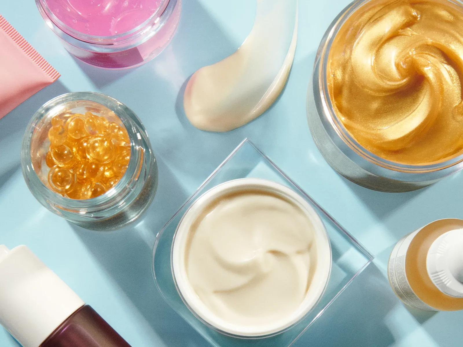 Olika skincareprodukter på ett blått underlag.