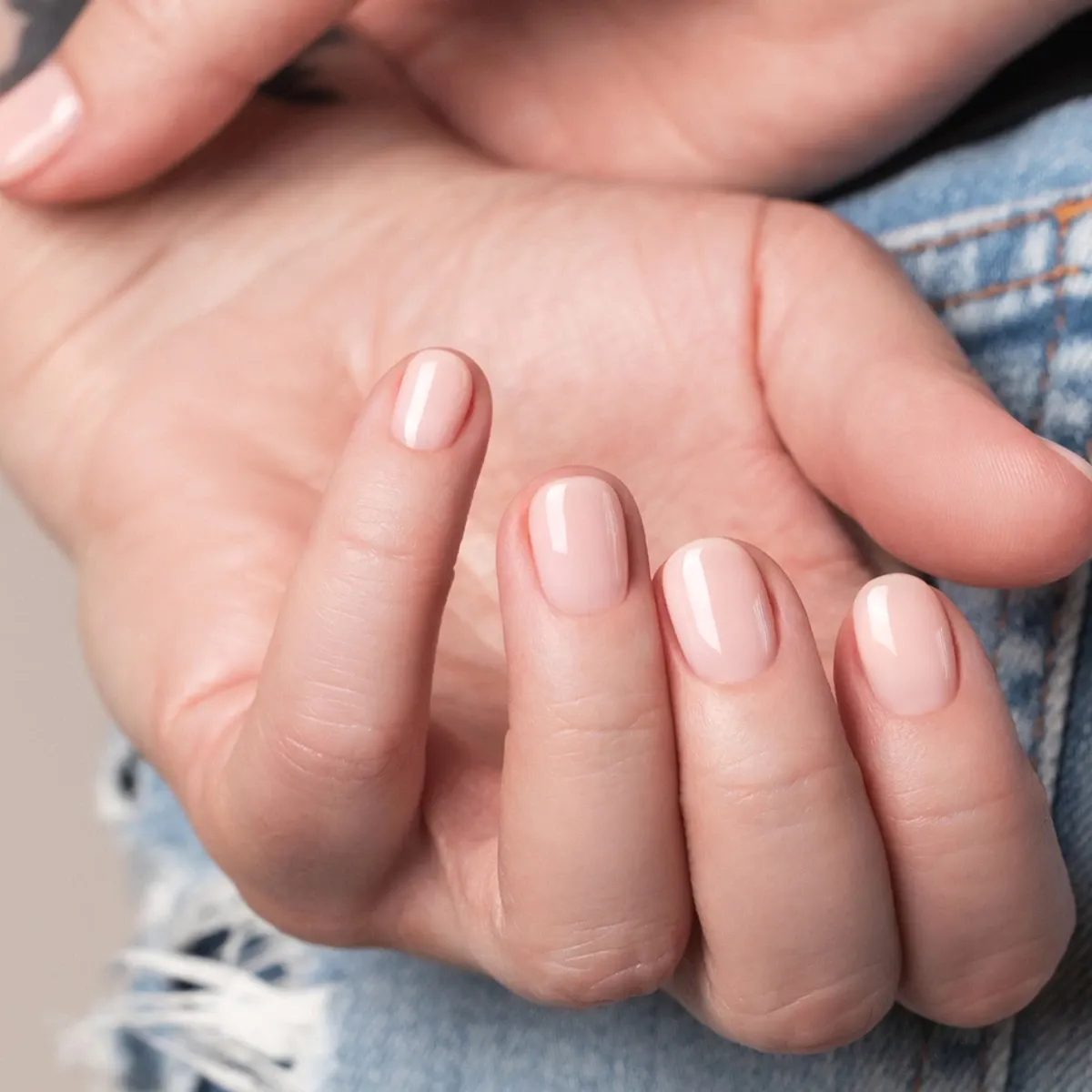 Närbild på en hand med ljusrosa nagellack.