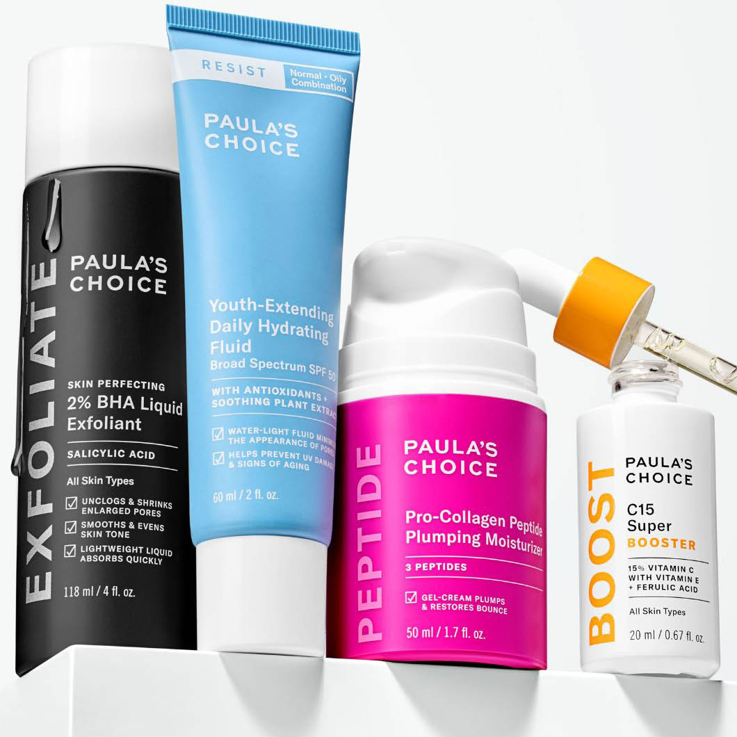 Fire hudpleieprodukter fra Paula’s Choice står på en hvit overflate: “Skin Perfecting 2% BHA Liquid Exfoliant”, “Youth-Extending Daily Hydrating Fluid SPF 50”, “Pro-Collagen Peptide Plumping Moisturizer” og “C15 Super Booster”. En pipette påfører serum i flasken.