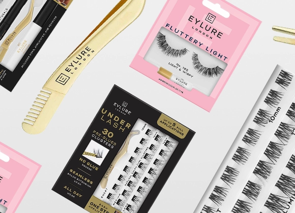 Bilde som viser forskjellige produkter fra Eylure London. På bildet vises pakker med falske øyenvipper, inkludert Eylure Fluttery Light No. 165 Light & Wispy i en rosa pakke, Eylure Under Lash 30 Pre-Glued Clusters i en svart pakke, og Eylure Naturals falske øyenvipper. Det er også en gullfarget applikator og kam fra Eylure. Bildet er arrangert med produktene spredt på en hvit bakgrunn.