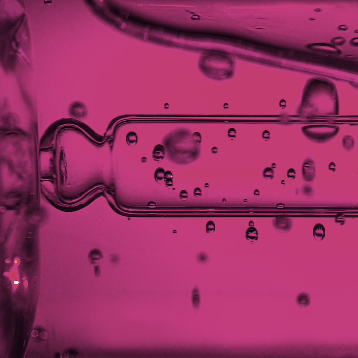 Nærbilde av pipette og rosa væskedråper.