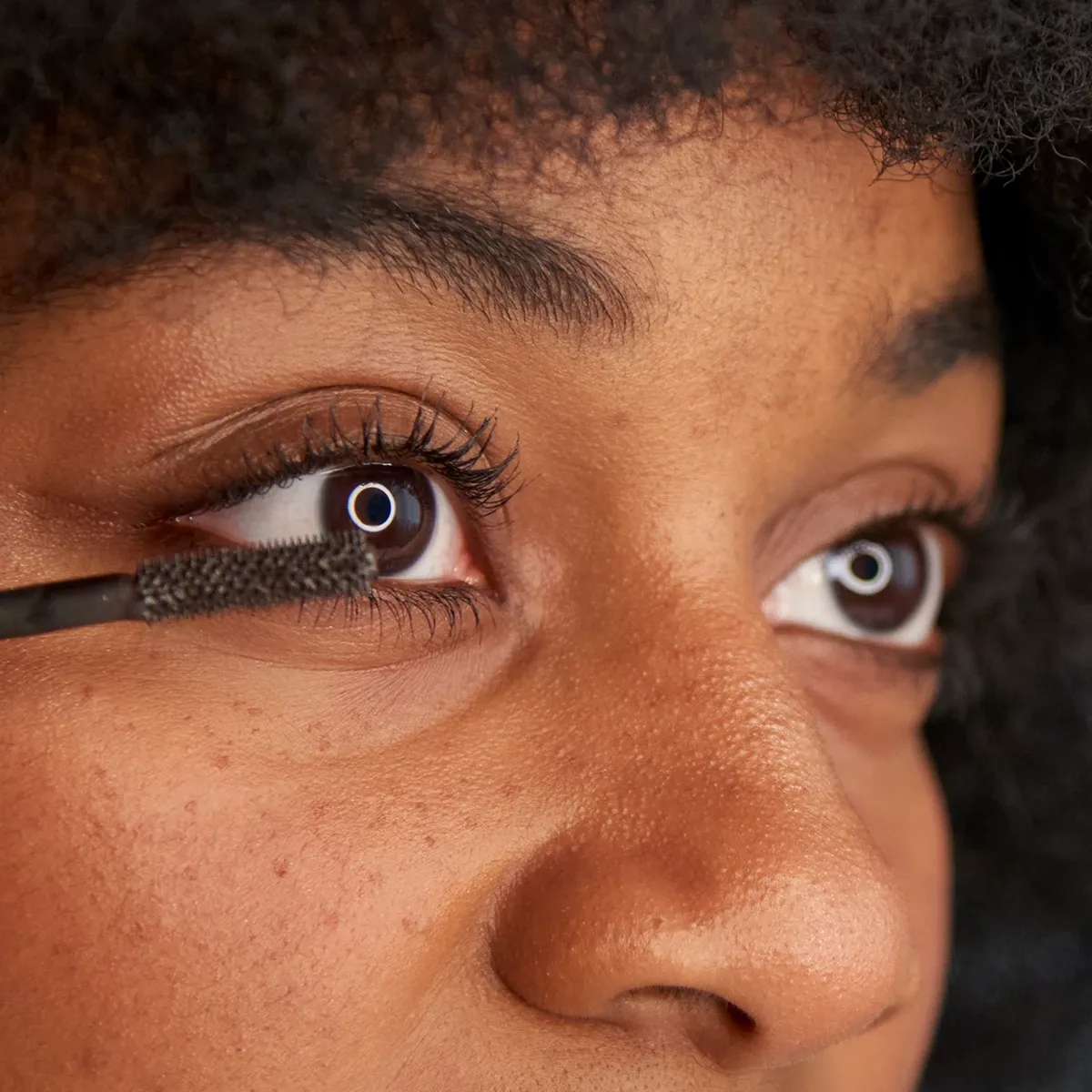 Närbild på en person som applicerar mascara på sina ögonfransar