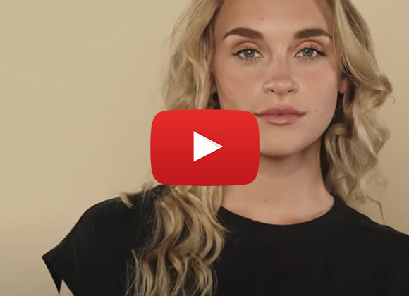 Tjej med ljust lockigt hår mot beige bakgrund.