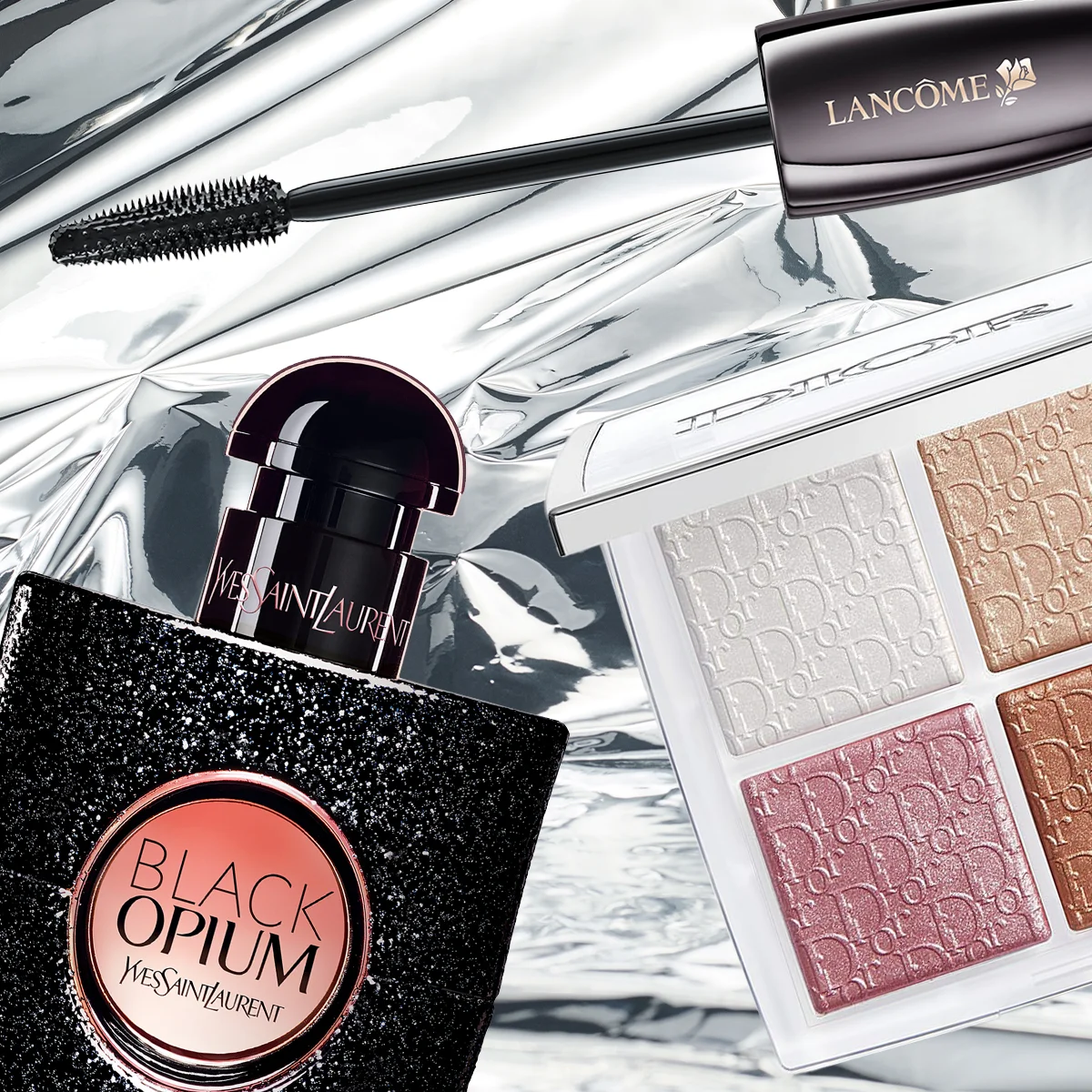 En lyxig beauty flatlay med Lancôme-mascara, YSL Black Opium-parfym och en Dior-palett med skimrande ögonskuggor i rosa, guld och beige toner, placerade på en glansig metallisk bakgrund.