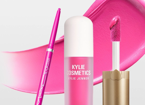 Kylie Cosmetics Supplе Kiss Lip Glaze -huulikiilto yhdessä vaaleanpunaisen "lipglazer"-huultenrajauskynän kanssa, applikaattori ja levitetty kiiltotekstuuri taustalla. Pakkauksessa lukee "KYLIE COSMETICS KYLIE JENNER SUPPLE KISS LIP GLAZE".