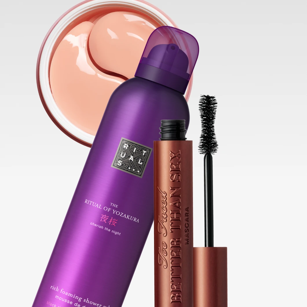 Vaaleanharmaata taustaa vasten esillä ovat Rituals The Ritual of Yozakura Rich Foaming Shower Gel, Too Faced Better Than Sex Mascara ja vaaleanpunaiset hydrogeeliset silmänympärysnaamiot.