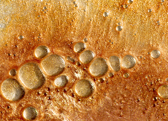 Närbild på guldig och brunglimrande brun-utan-sol-creme med bubblor.
