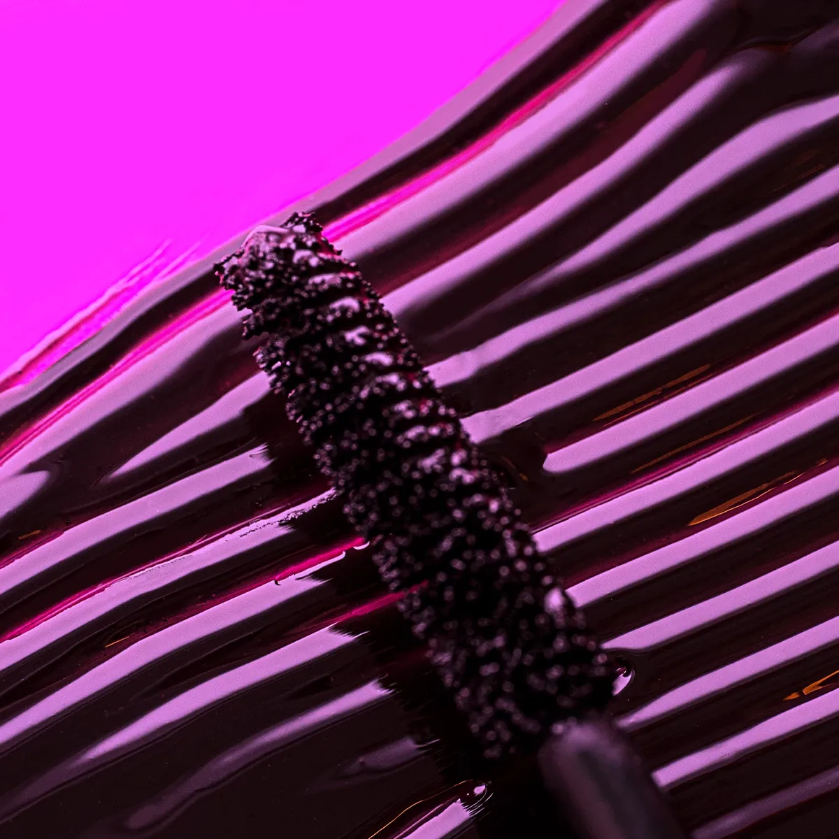 Mascara genomstruken med en mascaraborste i lila ljus 