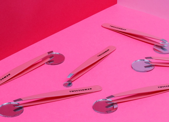Produktbild på fleraTweezerman pincetter som ligger utlagda mot färgstark cerise och röd bakgrund. 