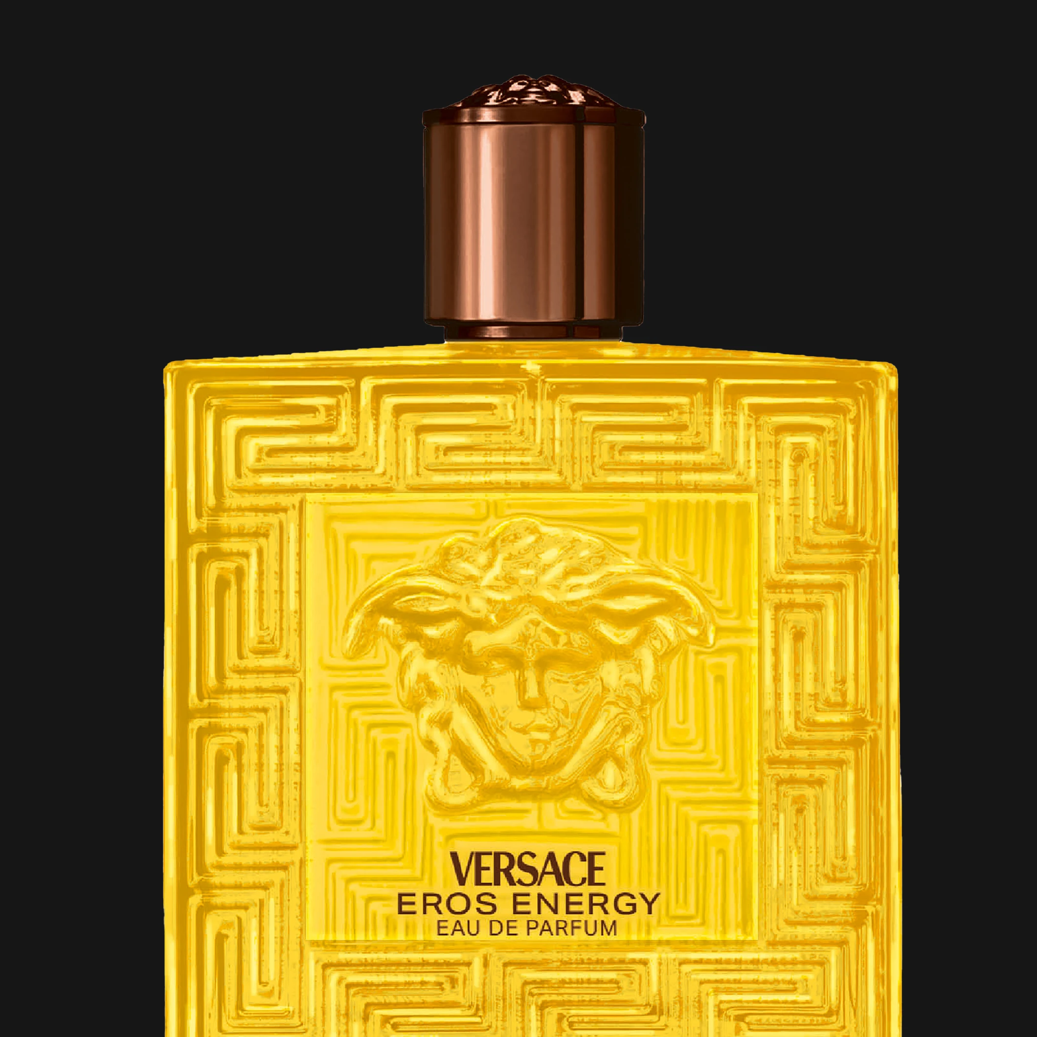 Versace Eros Energy Eau de Parfum keltaisessa lasipullossa Medusa-kuviolla ja koristeellisella pinnalla mustaa taustaa vasten. Näkyvä teksti sisältää “VERSACE”, “EROS ENERGY” ja “EAU DE PARFUM”.