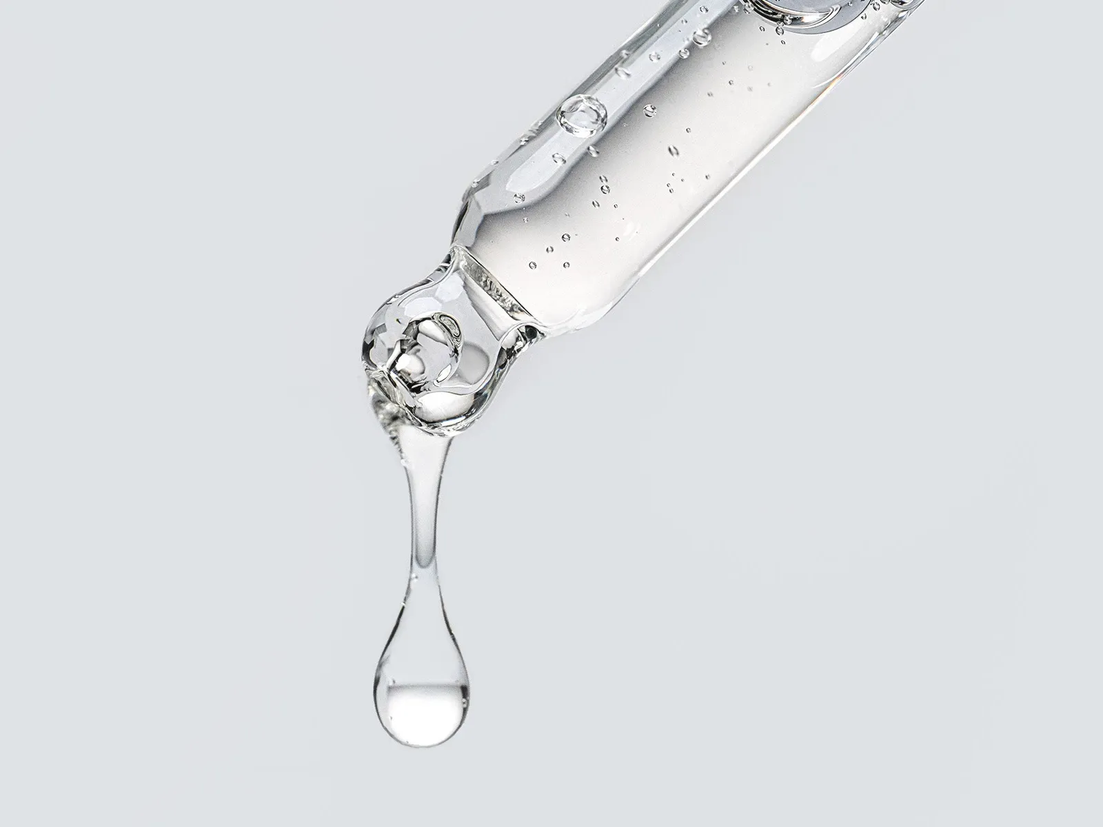 Et nærbilde av en pipette som slipper en dråpe klar væske.