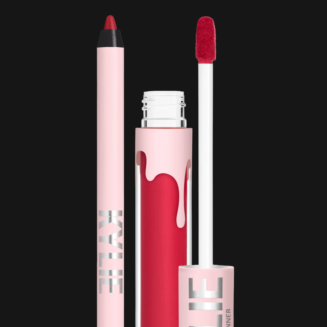 En rosa lipliner og en matchende rød flytende leppestift fra Kylie Cosmetics vises mot svart bakgrunn, med applikator og metalltekst på emballasjen.