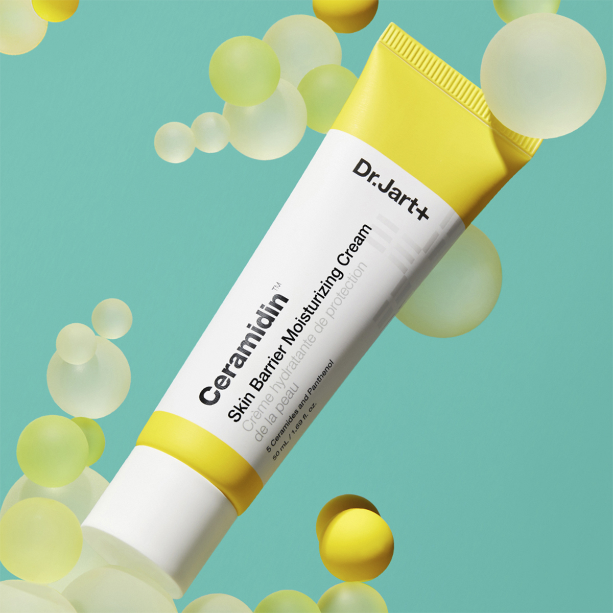 Tube med Dr.Jart+ Ceramidin Skin Barrier Moisturising Cream mot en turkis bakgrunn med gule og hvite bobler.
