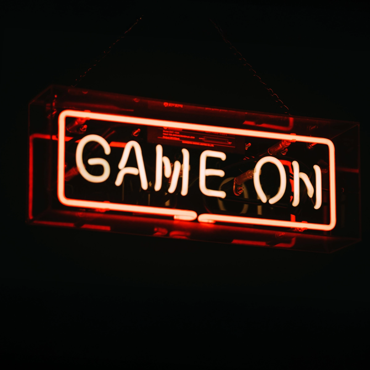 Röd och vit neonsskylt med texten “GAME ON” mot mörk bakgrund. Den upplysta skylten ger en modern och intensiv gamingkänsla.