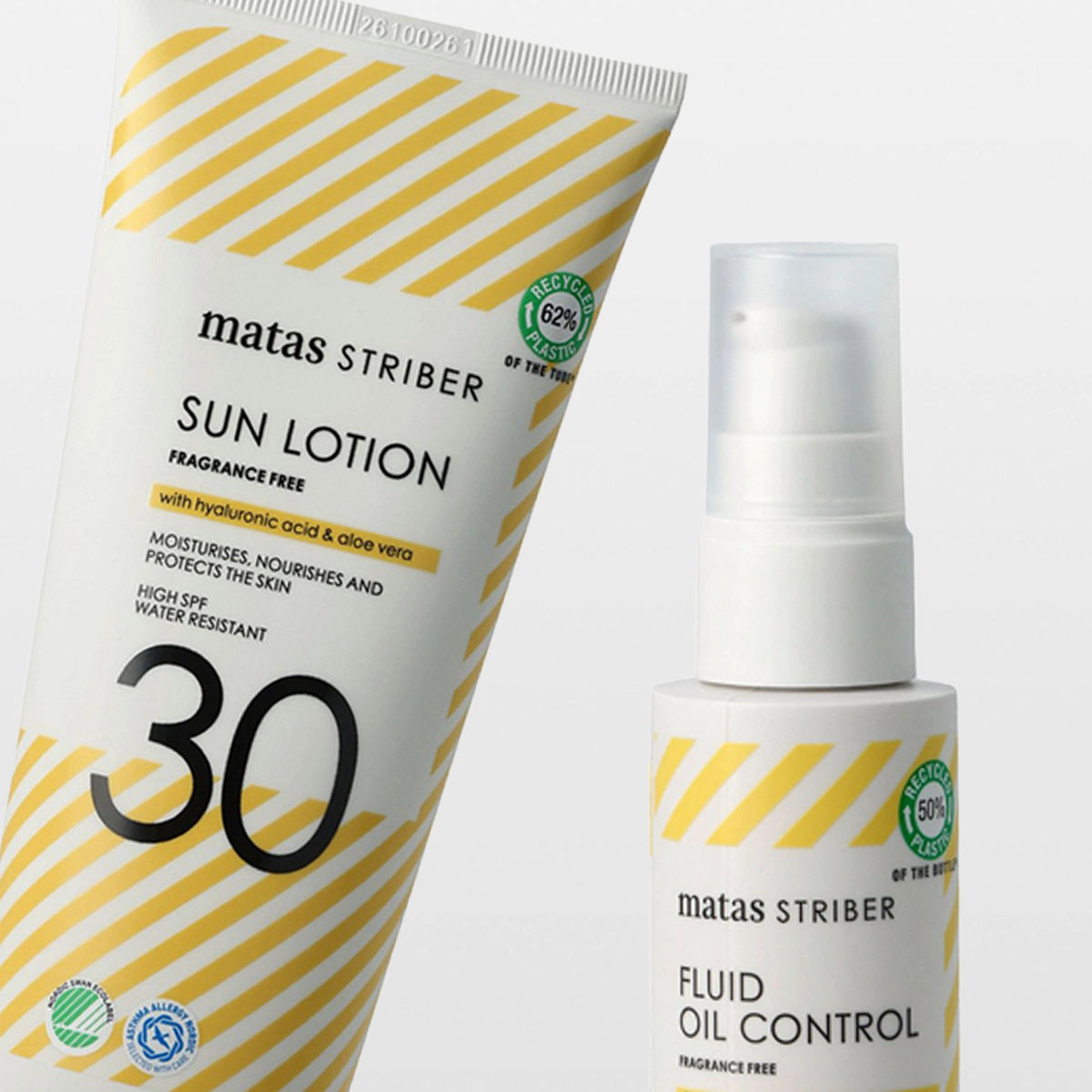 Tre solskyddsprodukter från Matas Striber: en tub “SUN LOTION”, en pumpflaska “FLUID OIL CONTROL” och en sprayflaska “SUN SPRAY”, alla med gula diagonala ränder och texten “FRAGRANCE FREE”. Förpackningarna visar “with hyaluronic acid & aloe vera”, “with glycerin and antioxidant vitamin E”, “HIGH SPF 30”, “WATER RESISTANT” samt märkningar som “RECYCLED 62% PLASTIC” och “RECYCLED 50% PLASTIC”.