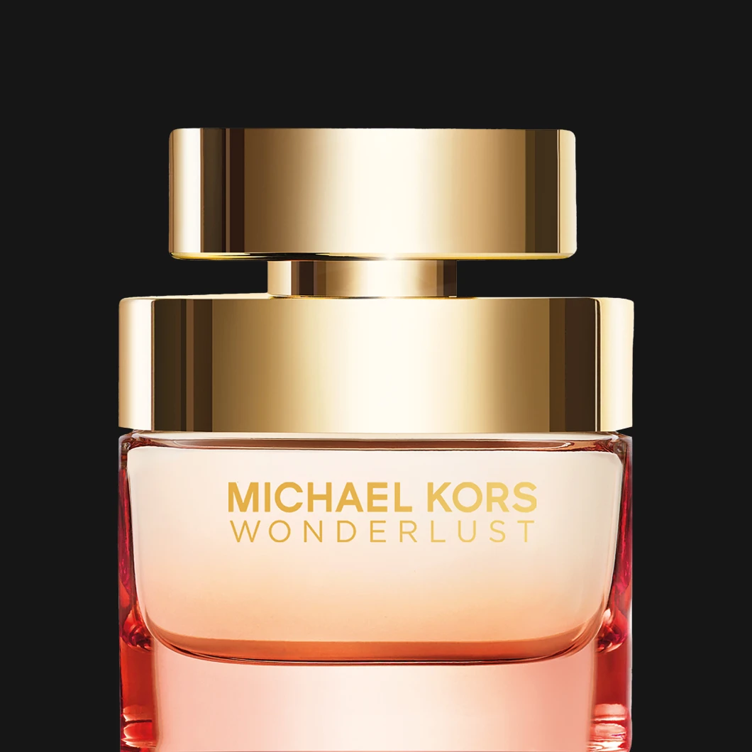 Parfymflaska Michael Kors Wonderlust i genomskinlig glasflaska med ljus roséfärgad vätska och guldfärgat lock.