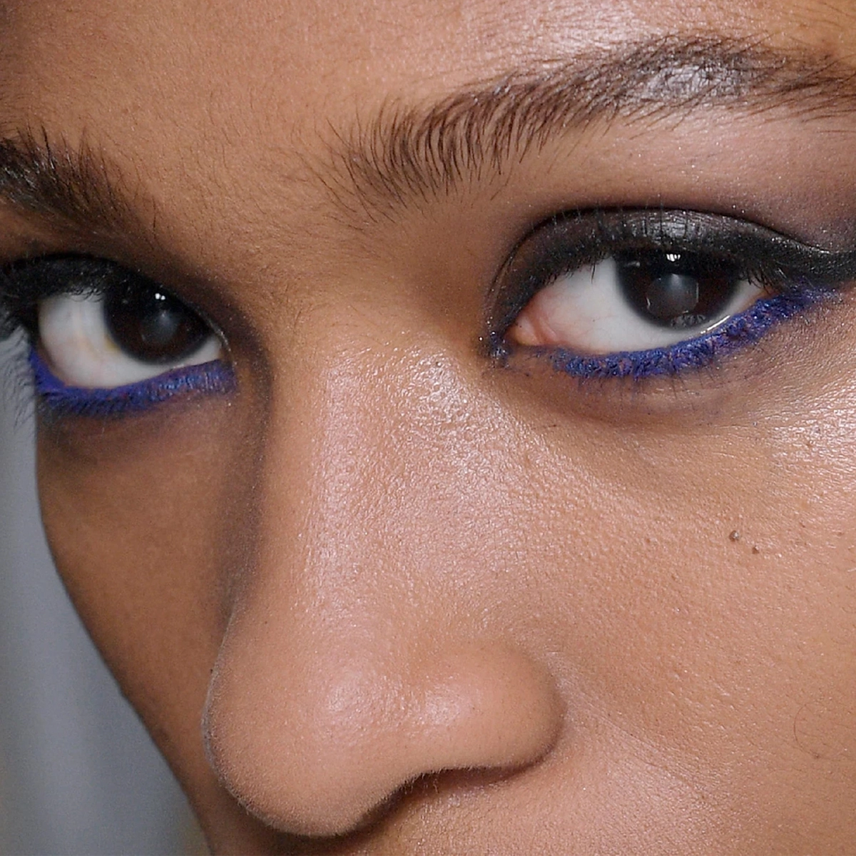Nærbilde av en kvinnes øyne, sminket med svart og blå eyeliner