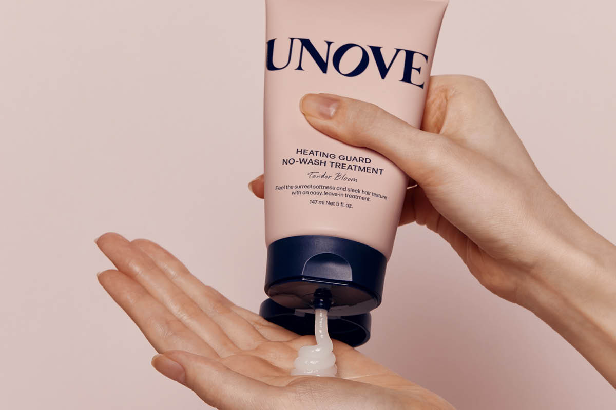 En hånd holder tuben “UNOVE HEATING GUARD NO-WASH TREATMENT Tender Bloom” og presser ut hvit hårpleiekrem i en åpen håndflate. På emballasjen vises også teksten “147 ml Net 5 fl. oz.”.