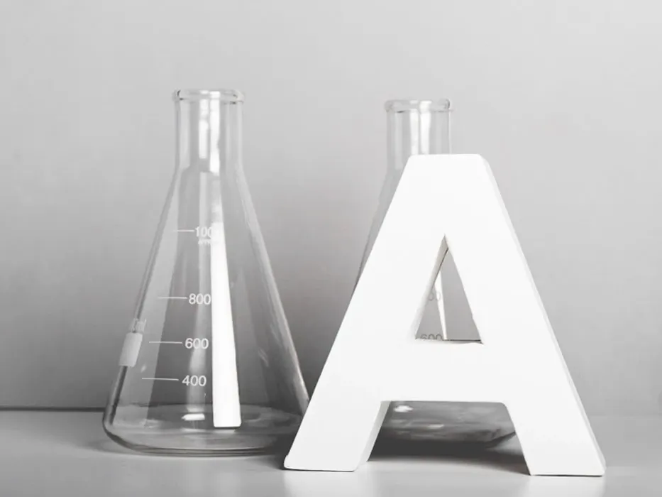 Iso A-kirjain kahden Erlenmeyer-pullon vieressä harmaalla alustalla ja taustalla.