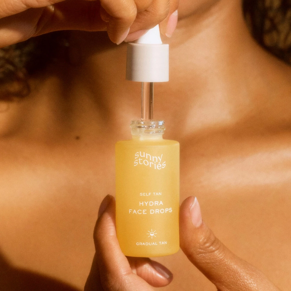En person håller en flaska med Sunny Stories Hydra Face Drops.