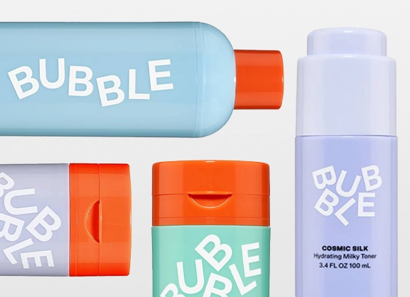 Flere hudpleieprodukter fra Bubble i pastellfarger plassert mot lys bakgrunn. Emballasje i blått, mintgrønt og lilla med oransje korker og hvit logotekst, inkludert en flaske merket “Cosmic Silk Hydrating Milky Toner 100 ml”.