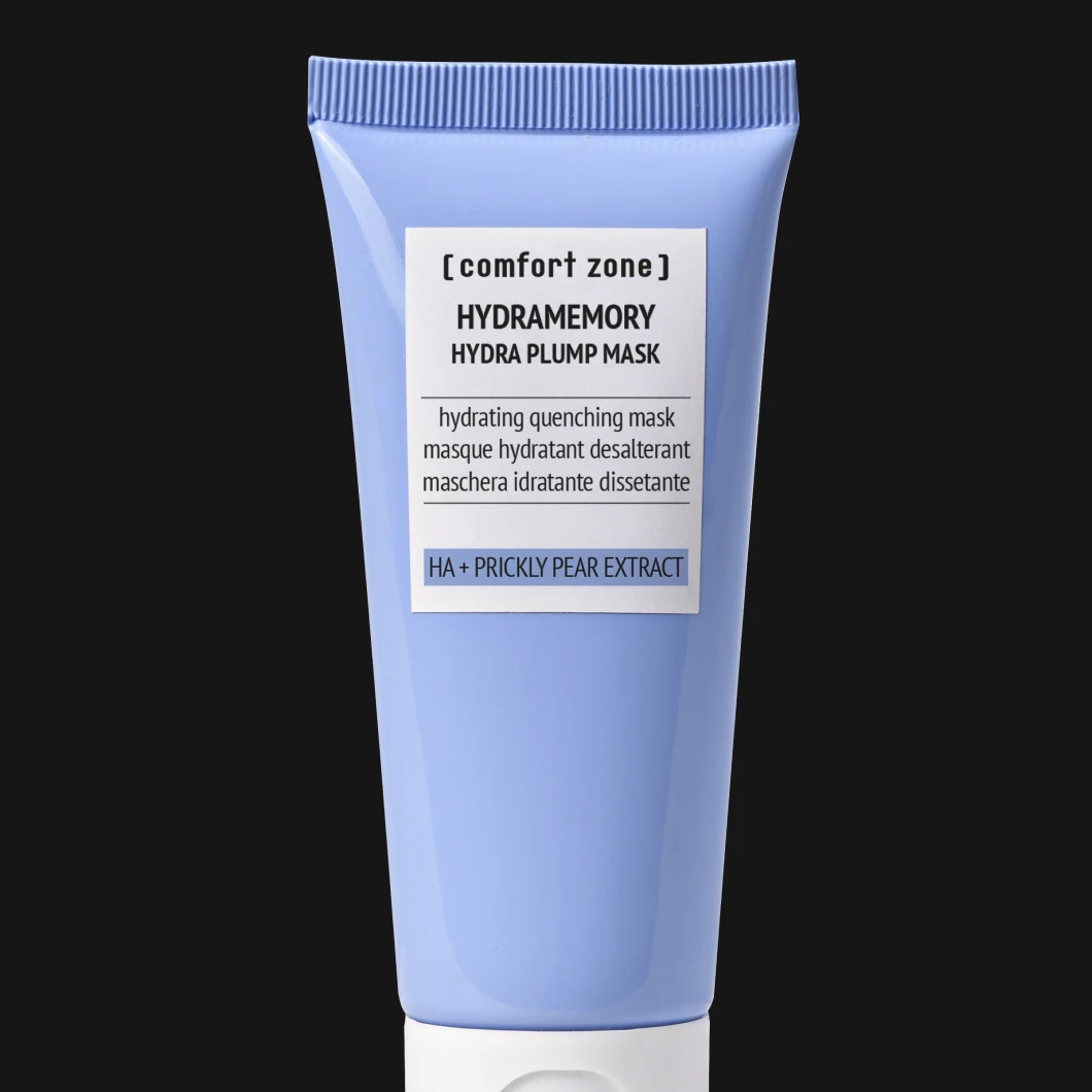 Ljusblå tub med texten “[comfort zone] Hydramemory Hydra Plump Mask” och “HA + Prickly Pear Extract”, placerad centrerat mot svart bakgrund.