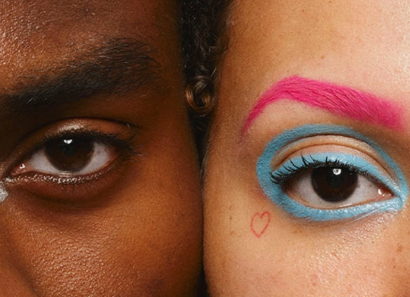 Nærbilde av to øyne og deler av ansikter side om side med fokus på øyesminke. Den ene har naturlig makeup, mens den andre har fargerik makeup med blå øyenskygge, rosa øyenbryn og en liten hjerteformet detalj ved øyet.