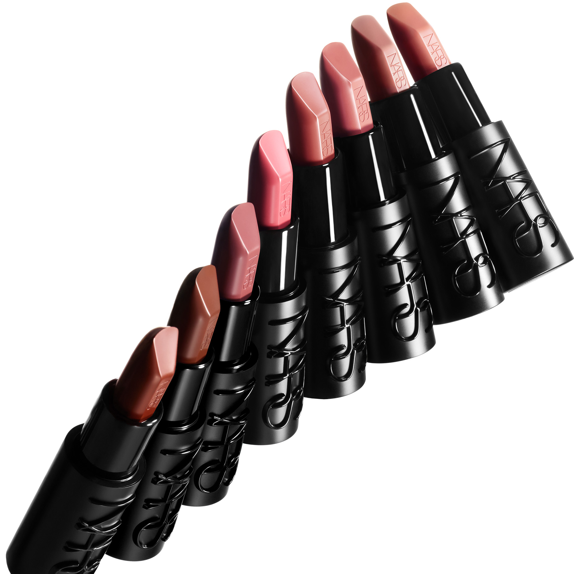 En rekke NARS leppestifter i nude-, rosa- og ferskentoner vises diagonalt mot en lys bakgrunn. De svarte hylsene er merket med den pregede logoen “NARS”, som også er synlig på leppestiftene.