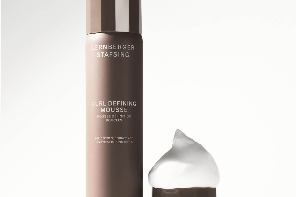 Lernberger Stafsing Curl Defining Mousse i brun flaska med lock bredvid och en klick vit hårmousse, med texten "CURL DEFINING MOUSSE", "MOUSSE DÉFINITION BOUCLES" och "FOR DEFINED, BOUNCY AND HEALTHY-LOOKING CURLS".